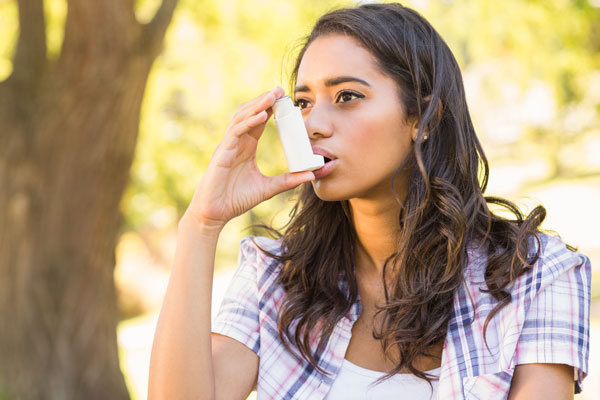 Woman using asthma inhaler