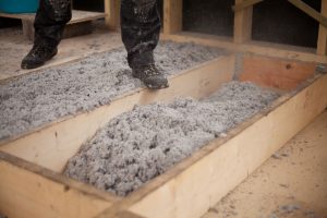 man stepping on rafters in attic to look at insulation