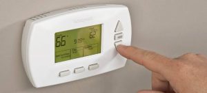 person pushing digital thermostat button